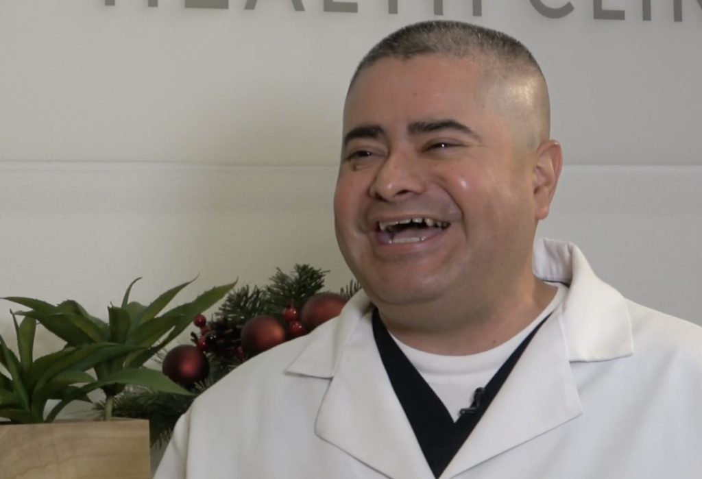Doctor Rafael Huezo from Mint Health Clinic in Bakersfield, California smiling in his lab coat